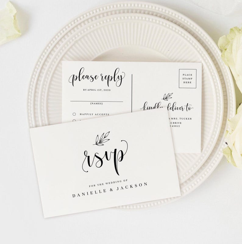 May include: A white RSVP card with black calligraphy that reads "RSVP" with a small floral design. The text "For the wedding of Danielle & Jackson" is printed below the RSVP.