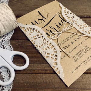 K&ouml;nnte beinhalten: Eine braune Papier-Hochzeitseinladung mit einer wei&szlig;en Spitzen&uuml;berlagerung. Die Einladung ist mit Schnur gebunden und tr&auml;gt den Text "Just Married" in schwarzer Kalligrafie. Die Einladung enth&auml;lt die Namen "Rissa & Cal" und das Datum "14. Oktober".