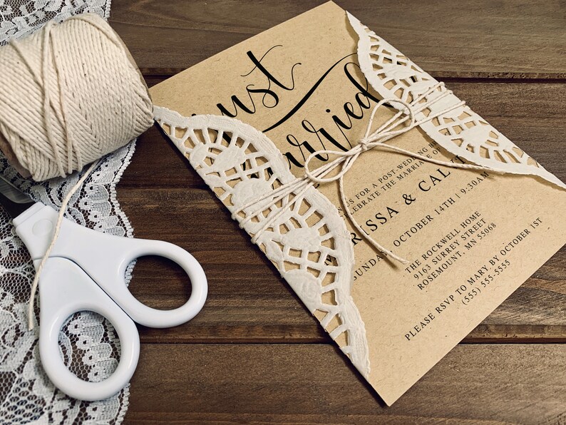 K&ouml;nnte beinhalten: Eine braune Papier-Hochzeitseinladung mit einer wei&szlig;en Spitzen&uuml;berlagerung. Die Einladung ist mit Schnur gebunden und tr&auml;gt den Text "Just Married" in schwarzer Kalligrafie. Die Einladung enth&auml;lt die Namen "Rissa & Cal" und das Datum "14. Oktober".