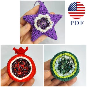 May include: A collection of handmade crochet ornaments. The image features a purple star, a red pomegranate, and a green circular design, each filled with decorative elements. The star has a white and clear center, and the pomegranate has red seeds.
