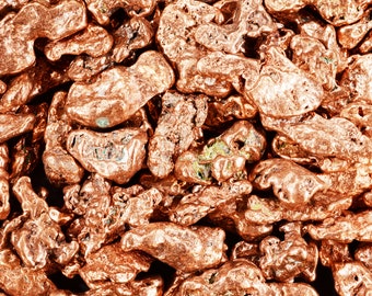 May include: Close-up of a pile of copper nuggets. The nuggets are a reddish-brown colour and have a rough, irregular texture.