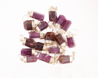 May include: A group of 15 purple and brown gemstone pendants with silver caps and loops. The pendants are arranged in a pile on a white background.