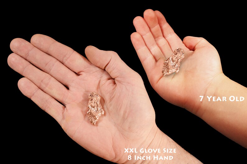 May include: Two hands holding a copper nugget. The hand on the left is an adult hand with an 8 inch circumference. The hand on the right is a child's hand, belonging to a 7 year old.