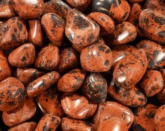 May include: Close-up of a group of red and black jasper tumbled stones. The stones are smooth and polished, with a variety of patterns and textures.