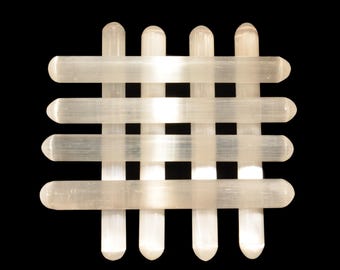 May include: A woven grid of translucent, rounded rectangular rods. The rods are arranged in a crosshatch pattern, creating a square shape. The background is solid black, highlighting the light-coloured material of the grid.