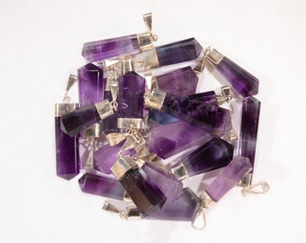 May include: A group of purple amethyst crystal pendants with silver bails. The pendants are in various shapes and sizes, and they are all clustered together.
