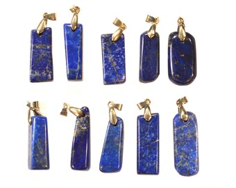 May include: Ten lapis lazuli pendants with gold-coloured bails. The pendants are various rectangular shapes, showing the deep blue colour and gold flecks typical of lapis lazuli. They are displayed against a white background.