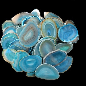 May include: A collection of blue agate slices with white and brown banding. The slices are arranged in a loose pile, with some overlapping.