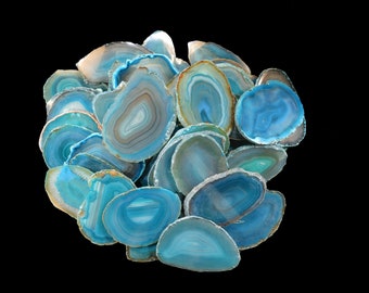 May include: A collection of blue agate slices with white and brown banding. The slices are arranged in a loose pile, with some overlapping.