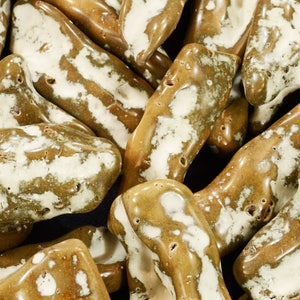 May include: A close-up of a pile of brown and white striped stones. The stones are smooth and have a natural, organic look.