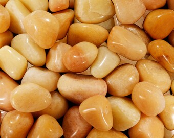 May include: A close-up of a collection of smooth, polished, light orange and yellow stones. The stones are various sizes and shapes, and they have a glossy finish.