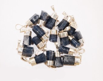 May include: A group of 17 dark blue gemstone pendants with silver caps and loops. The pendants are arranged in a loose pile on a white surface.