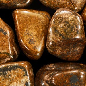 May include: Close-up of a group of tumbled stones with a brown and black marbled pattern.