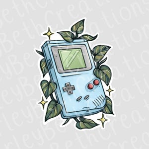 May include: A light blue handheld video game console sticker with a green screen, red buttons, and a directional pad. Green leaves and gold stars surround the console, creating a nature-inspired design.
