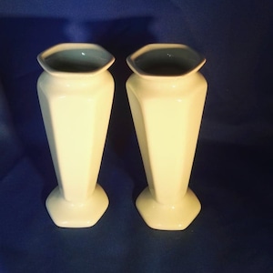 May include: Two white ceramic vases with a light blue glaze inside. The vases are octagonal in shape and have a rounded base.