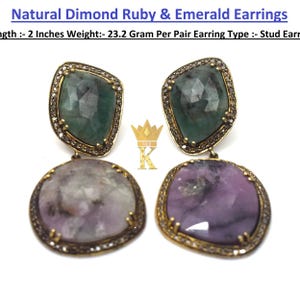 Könnte beinhalten: Natural Dimond Ruby & Emerald Earrings, 2 Zoll, 23,2 Gramm pro Paar, Ohrstecker. Zwei Ohrringe mit facettierten grünen Smaragden und violetten Rubinen in dunklen Metallfassungen mit kleinen eingebetteten Steinen und goldenem Kronenlogo.