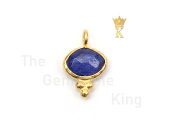 May include: Gold pendant with a blue gemstone and three small gold balls hanging from the bottom.