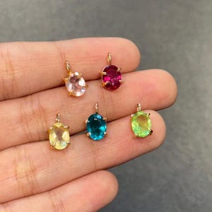 Puede incluir: Cinco colgantes de piedras preciosas de forma ovalada con engastes de oro. Las piedras preciosas son rosa, roja, amarilla, azul y verde.
