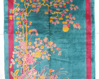 May include: A teal blue rug with a pink and yellow floral design. The rug has a pink border.
