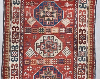Könnte beinhalten: Ein traditioneller roter, blauer und weißer Teppich mit komplizierten geometrischen Mustern. Der Teppich hat ein zentrales Medaillon und einen Rand mit sich wiederholenden Motiven.