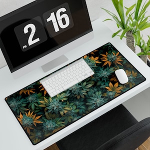 May include: A green and yellow leafy design mousepad with a white keyboard and a white mouse on top. The mousepad is on a white desk with a black computer monitor in the background.