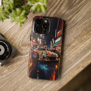 May include: A black iPhone case with a colorful illustration of a yellow car driving through a city street at night. The case features a camera lens cutout and a black background.