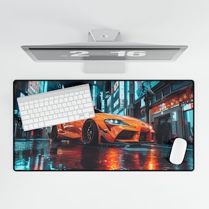 May include: A black and orange gaming mouse pad with a city skyline and a bright orange sports car in the foreground. The mouse pad has a reflective surface that shows the city lights.