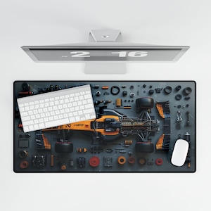 May include: A black and grey mouse mat featuring a Formula 1 race car in orange and black, surrounded by various car parts and tools. The mouse mat also features a white keyboard with the text "<MFEP" on the bottom right corner.