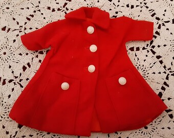 Könnte beinhalten: Ein roter Puppenmantel mit weißen Knöpfen und Taschen. Der Mantel hat einen Kragen und lange Ärmel.