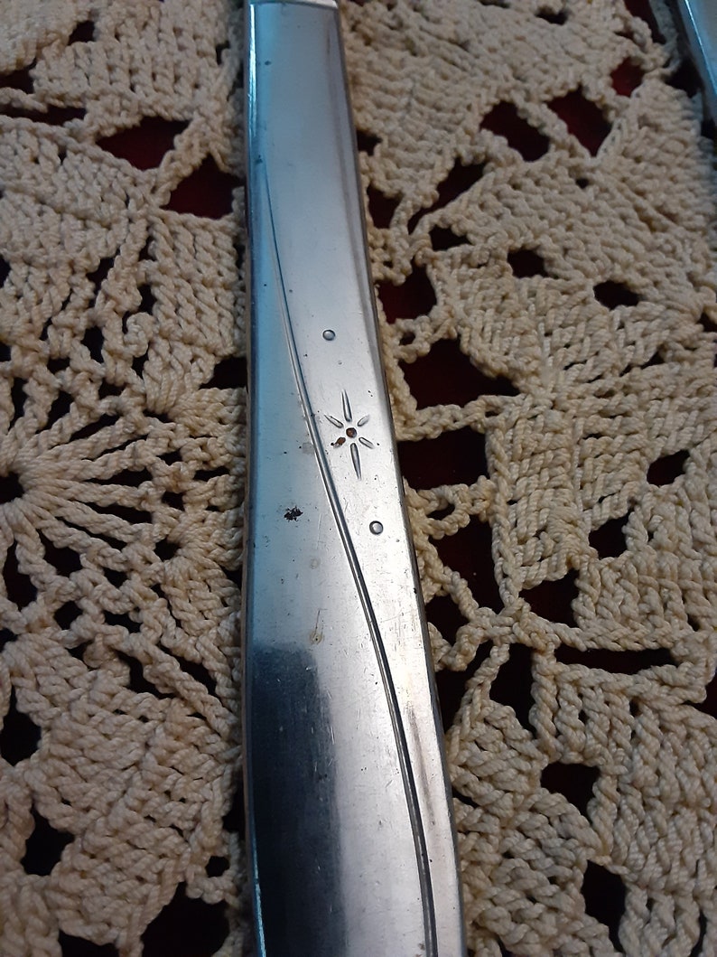 May include: Close-up of a silver knife with a star-shaped design on the handle.