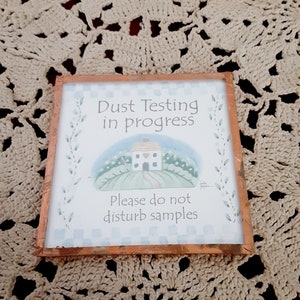 Puede incluir: Un cartel enmarcado con una ilustración de acuarela de una casa con un corazón en la puerta. El cartel dice "Dust Testing in progress. Please do not disturb samples."