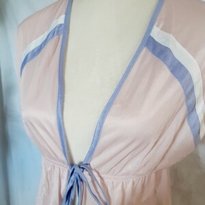 May include: A light pink robe with a deep V-neckline and a tie at the waist. The robe has blue and white trim around the neckline and sleeves.