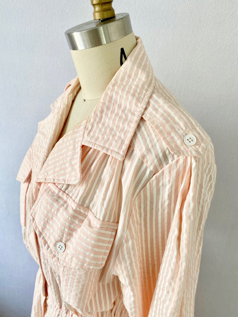 Pu&ograve; includere: Una camicia a maniche lunghe a righe rosa e bianche con colletto e due tasche con bottoni. La camicia ha una vestibilit&agrave; rilassata ed &egrave; realizzata in un tessuto leggero.