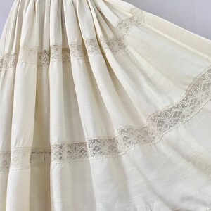 May include: A white cotton dress with a full skirt and lace trim. The dress has a fitted bodice and short sleeves.