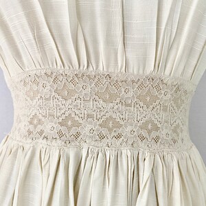 May include: A white dress with a lace trim around the waist.
