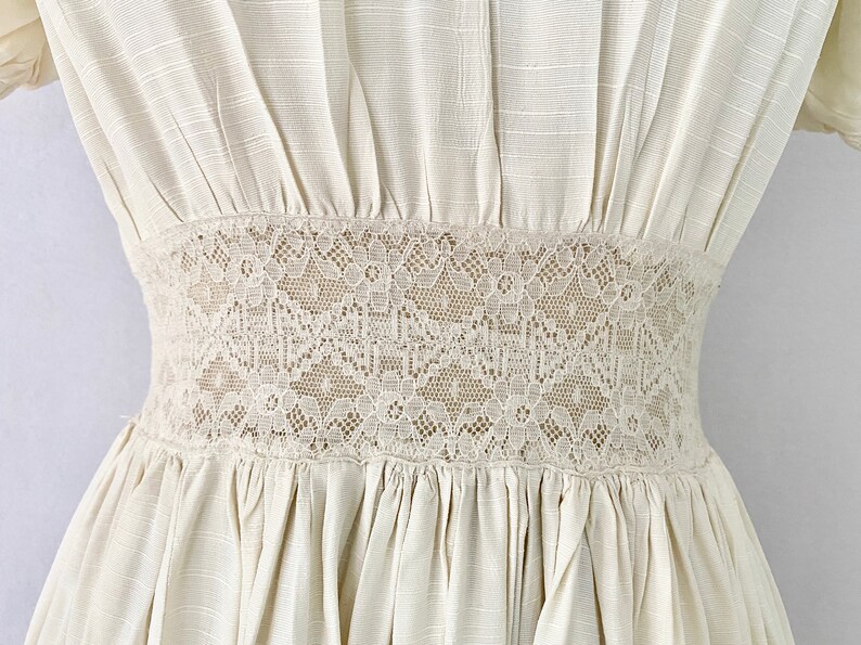 May include: A white dress with a lace trim around the waist.