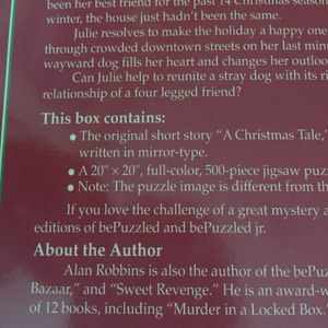 K&ouml;nnte beinhalten: Eine rot-wei&szlig;e Schachtel mit dem Text "A Holiday Story for a Homeless Heart" und einer Beschreibung des Inhalts, darunter eine Kurzgeschichte, ein 50,8 cm x 50,8 cm gro&szlig;es Puzzle und Informationen &uuml;ber den Autor Alan Robbins.