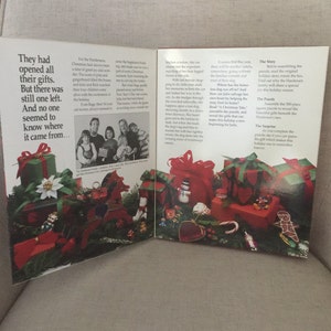 K&ouml;nnte beinhalten: Ein offenes Buch mit einer weihnachtlichen Illustration auf dem Umschlag. Das Buch zeigt ein rotes und gr&uuml;nes Farbschema mit einer Vielzahl von Weihnachtsdekorationen, darunter Geschenke, einen Schneemann und einen Zuckerstock. Der Text auf dem Umschlag lautet "Die Geschichte" und "Das Puzzle".