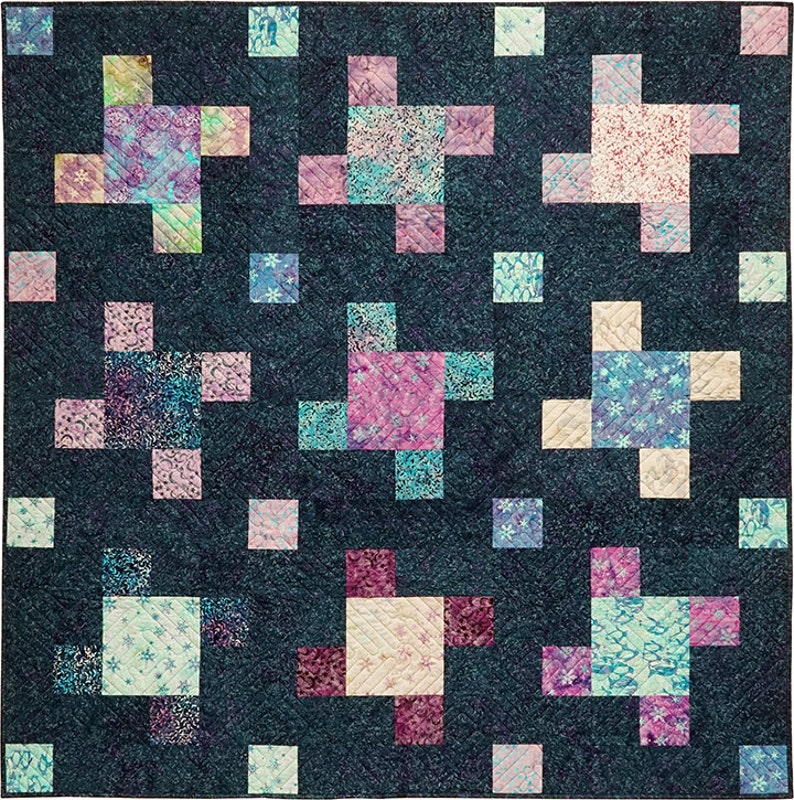 May include: A quilt with a dark blue background and a repeating pattern of colorful squares arranged in a cross shape. The squares are in shades of pink, blue, and green.