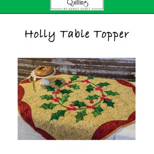 May include: A quilted table topper with a holly wreath design. The topper is 33 inches by 33 inches and features a red and green color scheme. The text "Holly Table Topper" is written in black at the top of the image. The text "MQ-144" is written in black at the bottom left of the image. The text "Finished Size: 33" x 33" is written in black at the bottom center of the image. The text "Intermediate" is written in black at the bottom right of the image.