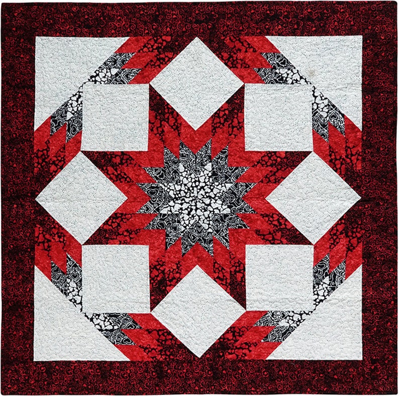 K&ouml;nnte beinhalten: Eine rote, wei&szlig;e und schwarze Steppdecke mit einem Sternmuster in der Mitte. Die Steppdecke ist aus Stoff mit einem kleinen Herzmuster gefertigt.