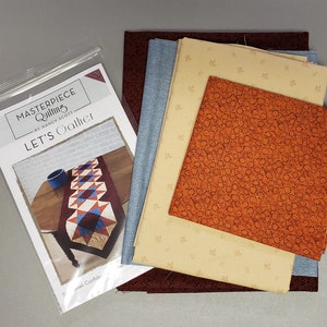 May include: A quilting kit for a table runner called "Let's Gather" by Nancy Scott. The kit includes fabric in shades of brown, orange, blue, and beige. The pattern is for a table runner with a geometric design.
