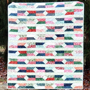 May include: A colorful quilt with a geometric pattern of white, green, blue, pink, and red. The quilt is made of fabric with a floral print.