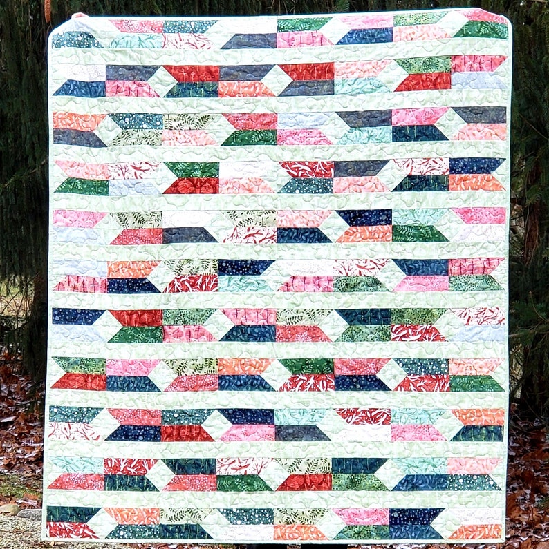 May include: A colorful quilt with a geometric pattern of white, green, blue, pink, and red. The quilt is made of fabric with a floral print.