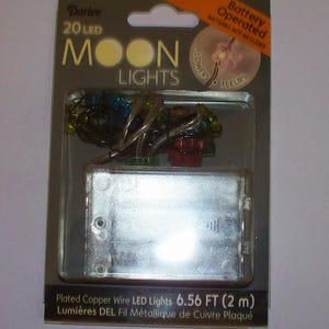 May include: A package of Darice Moon Lights, featuring 20 LED lights on plated copper wire. The package includes a battery compartment and states the lights are 2 metres long. The package is labeled "Battery Operated" and "Batteries Not Included."