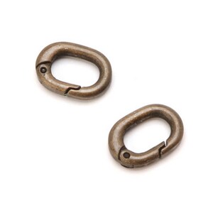 May include: Two antique gold-toned metal oval-shaped clasps with a spring-loaded closure.