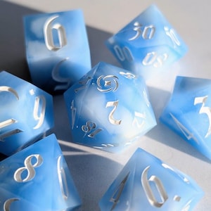 Puede incluir: Un conjunto de siete dados poliédricos azules y blancos veteados. Cada dado presenta números blancos grabados. Los dados están dispuestos sobre una superficie clara, con sombras.