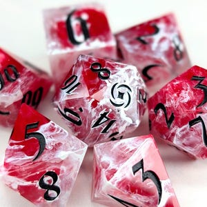 May include: Set of seven polyhedral dice with a red and white marbled design. Each die features black numbering. The dice are designed for tabletop role-playing games.
