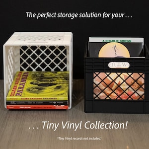 May include: Two small, square storage crates, one white and one black, are displayed. The white crate holds vinyl records, while the black crate contains vinyl records. Text on the image reads, "The perfect storage solution for your... Tiny Vinyl Collection!"