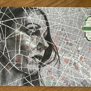 Può includere: Un disegno in bianco e nero di un viso di donna sovrapposto a una mappa di Parigi. La mappa è etichettata "Vista del centro di Parigi presa dall'aria".